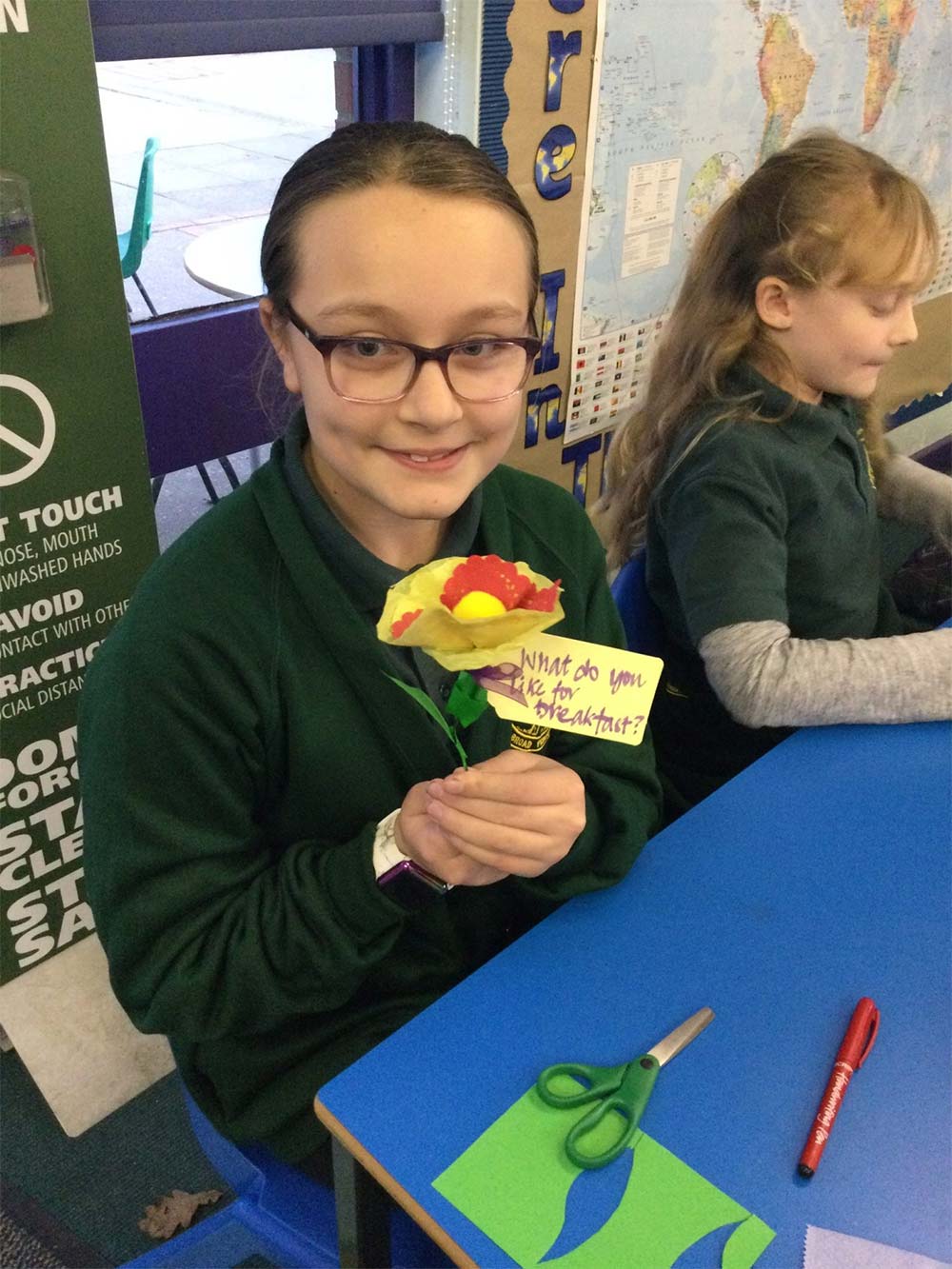 School pupil holds a paper flower with a question attached to it