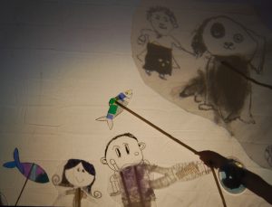 A shadow puppet display featuring colourful fish, a dog with a black patch on one eye and several characters from the Lowestoft Folk story