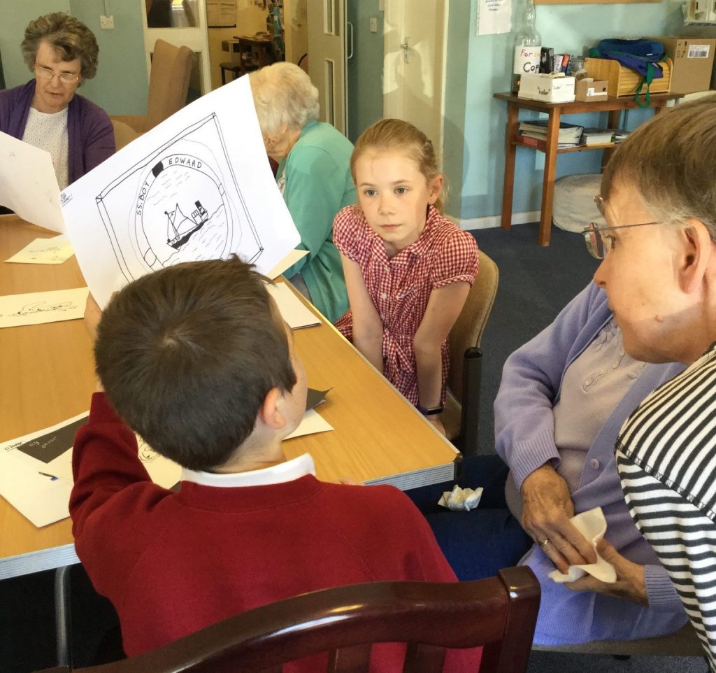 A young boy is showing his drawing of a boat inside a round frame, as another child and adults look on