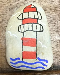 A picture of a lighthouse drawn on to a white sea pebble