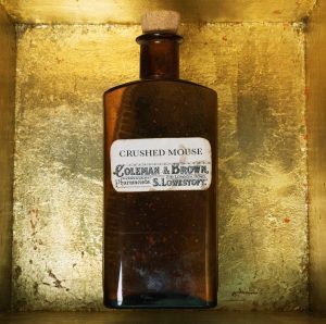 An old fashioned chemist's bottle, with a label reading Crushed Mouse, inside a box lined with gold leaf