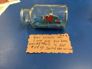 A cardboard boat in a glass bottle with a message that reads Dear Sailors how long have you been sailing for? This is for every sailor. Love William