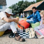 An adult and a child playing chess on a large outdoor chess set