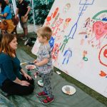 Adult and child next to a large cpaint your own monster canvas