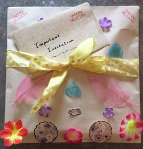 A large handmade envelope, decorated with flowers and feathers, and an Important Invitation