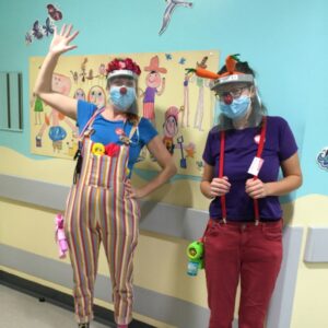 2 clown doctors in a bright blue hospital hallway