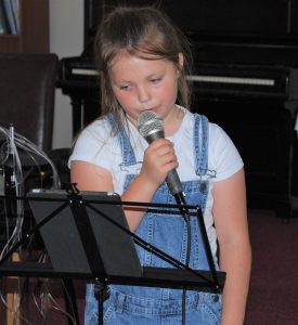 A young girl singing into a microphone