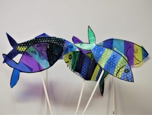 A collection of multicoloured fish, made on clear acetate decorated with strips of coloured acetates, making the fish translucent