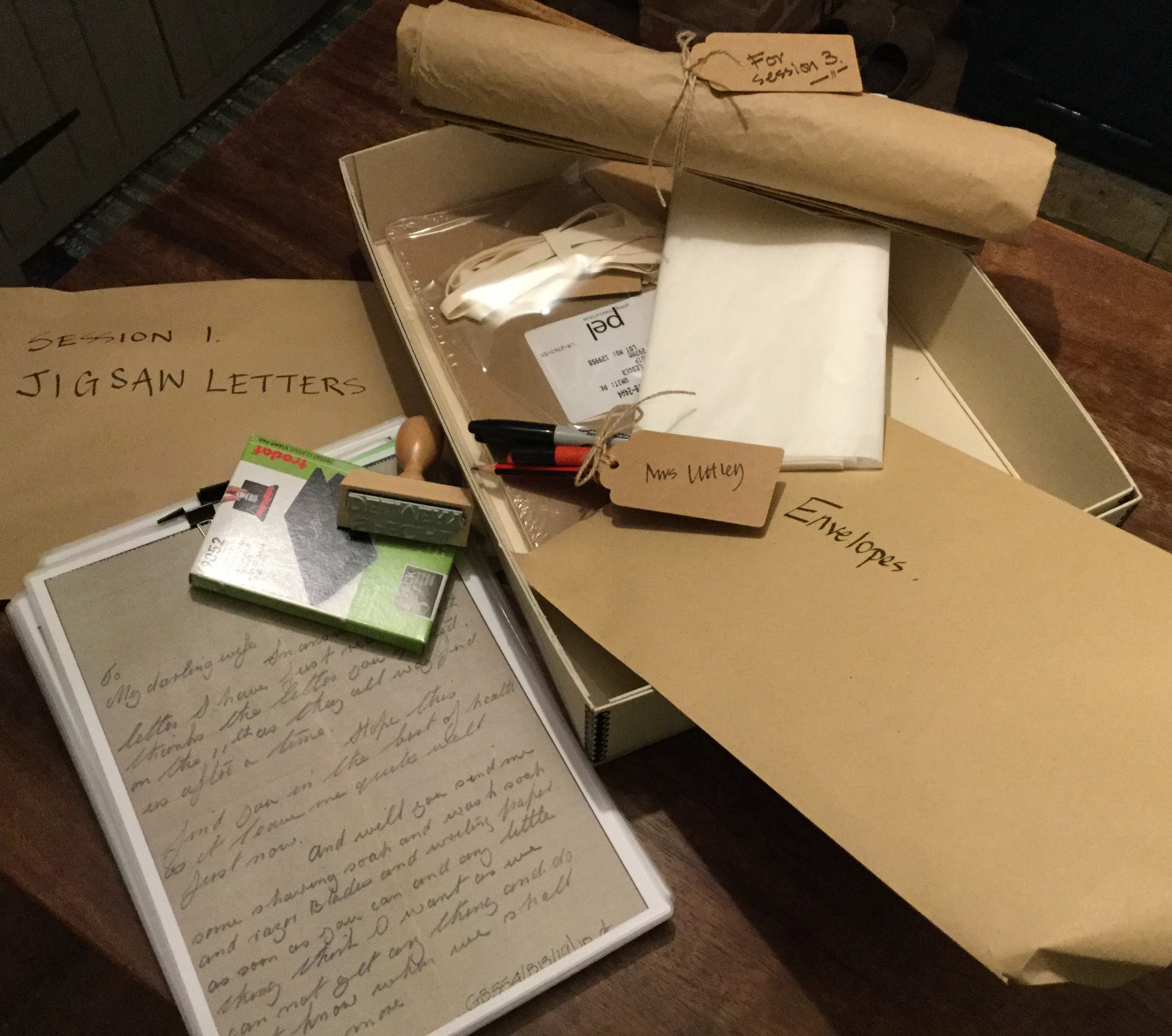 A collection of brown envelopes, pens and paper, plus a copy of a hand-written letter
