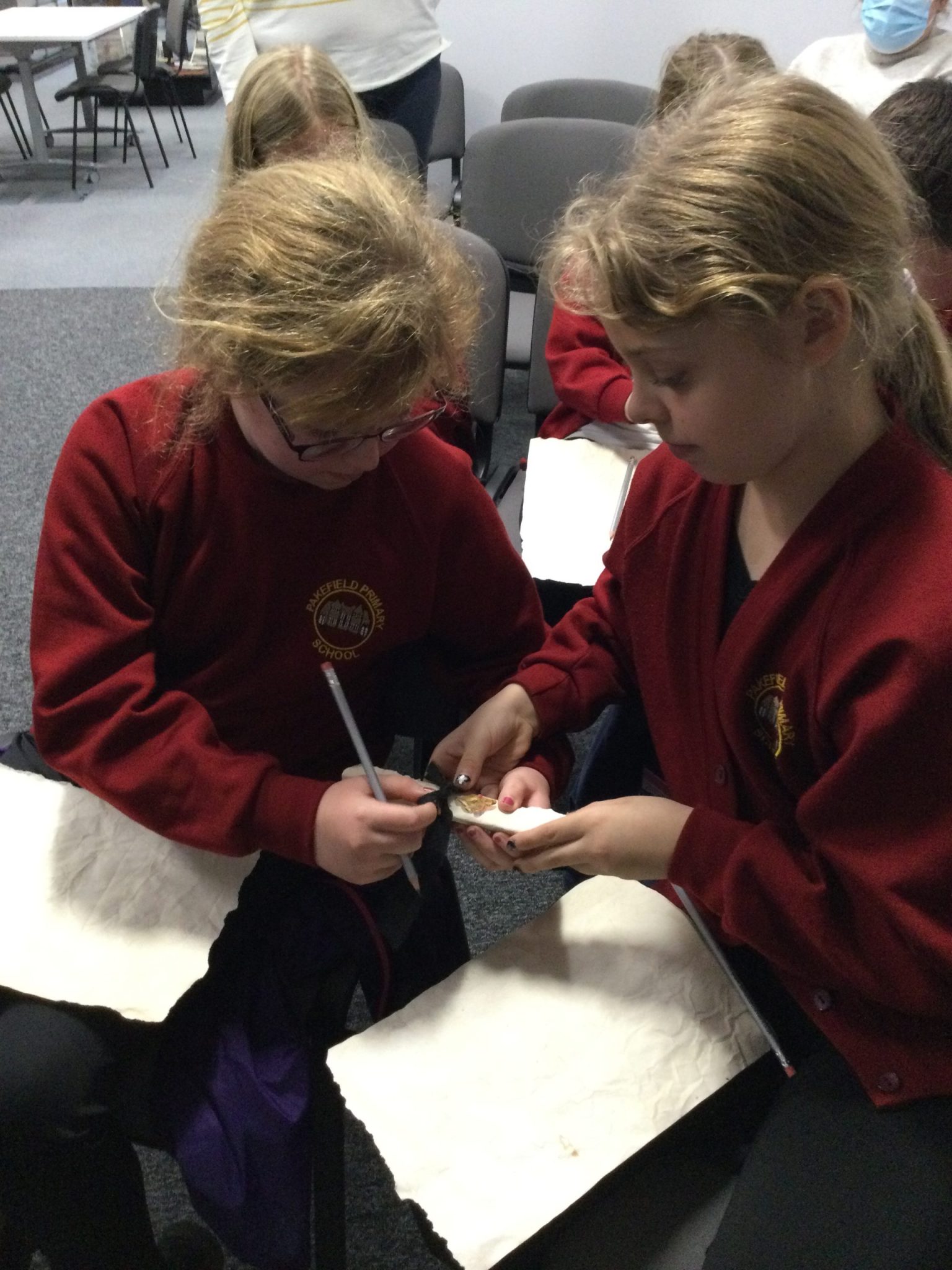 Two young girls opening an old-fashioned scroll