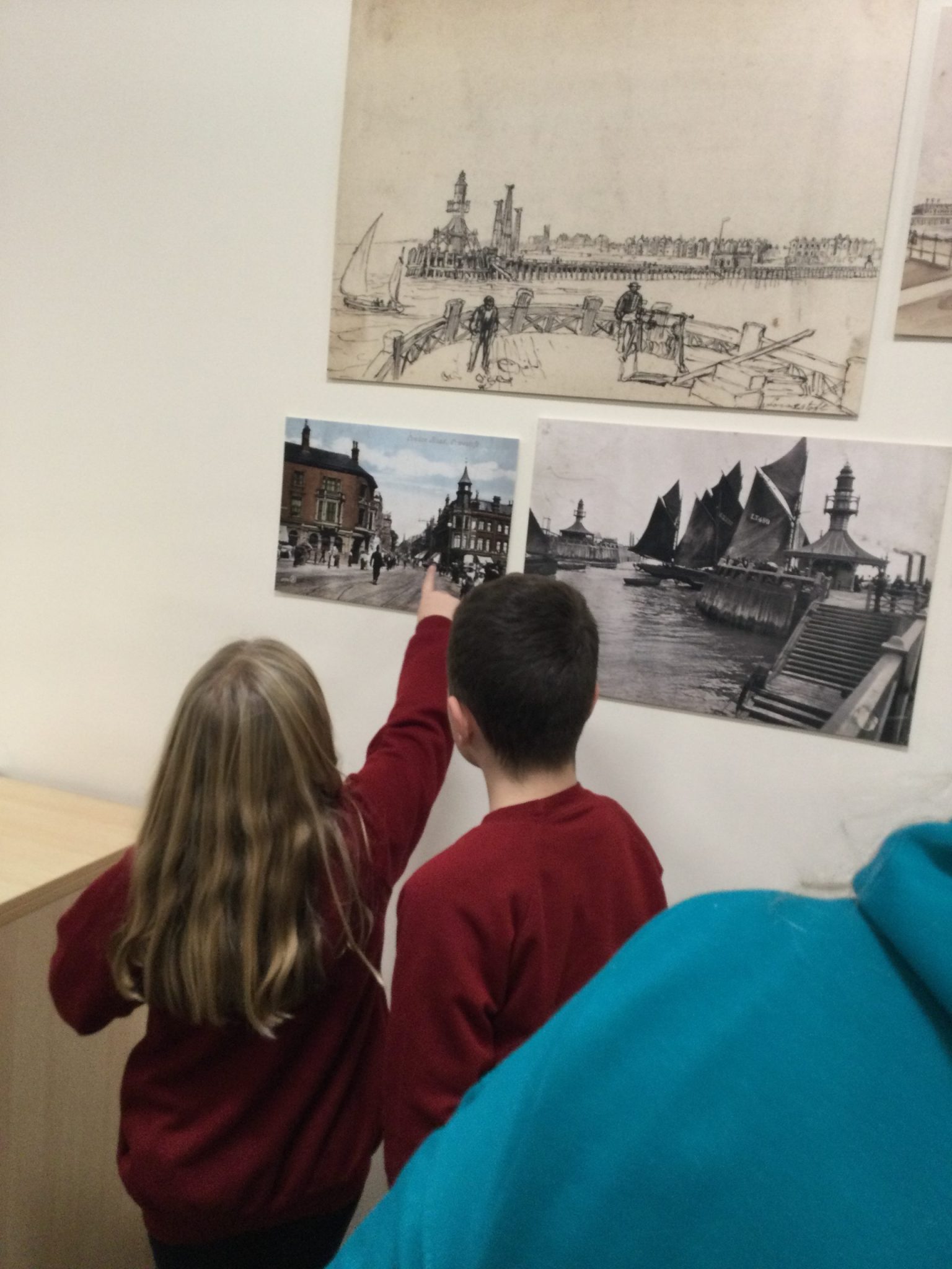 Two school children examining images of Lowestoft