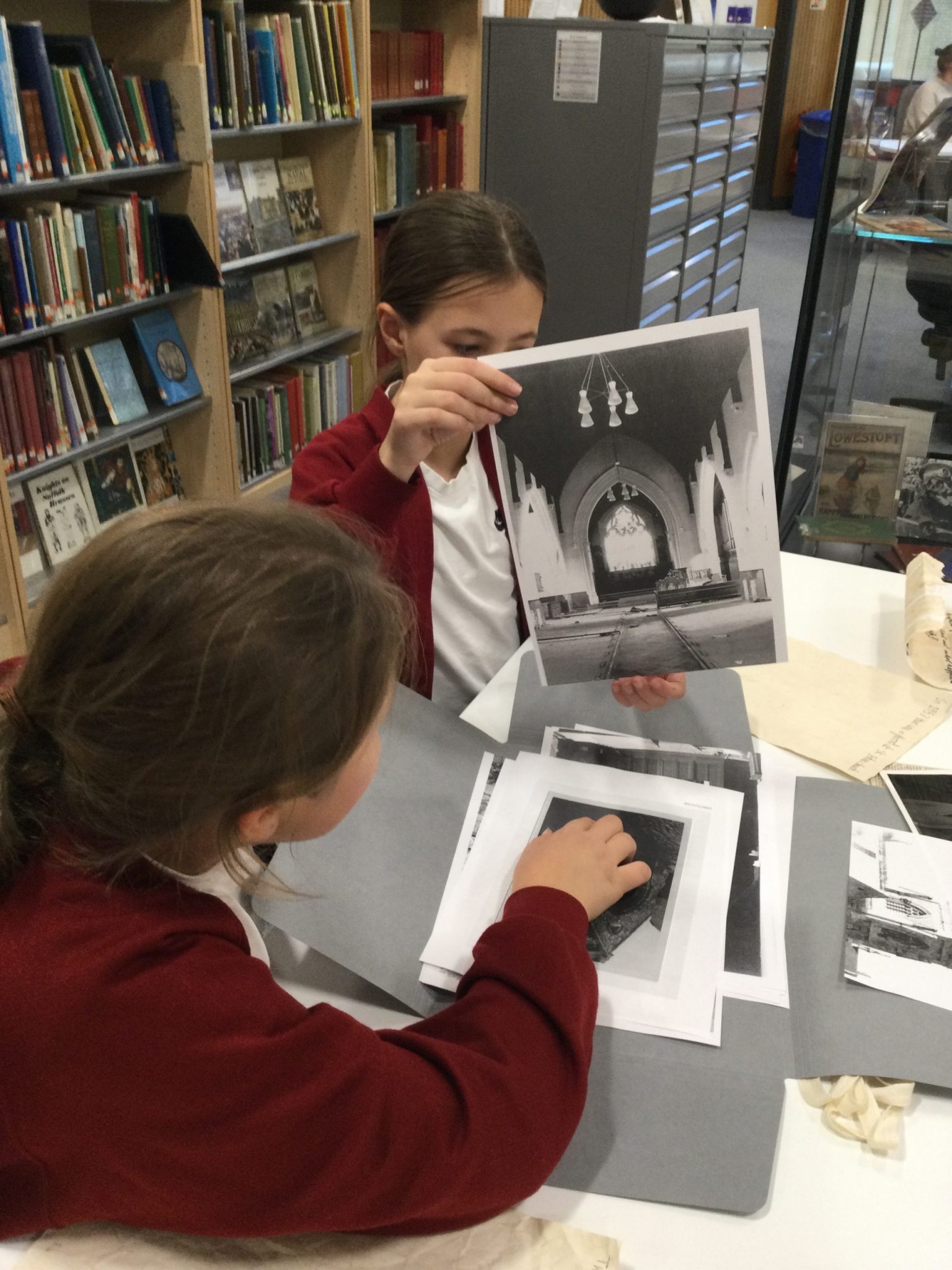 Two school children looking at monotone pictures of a church interior