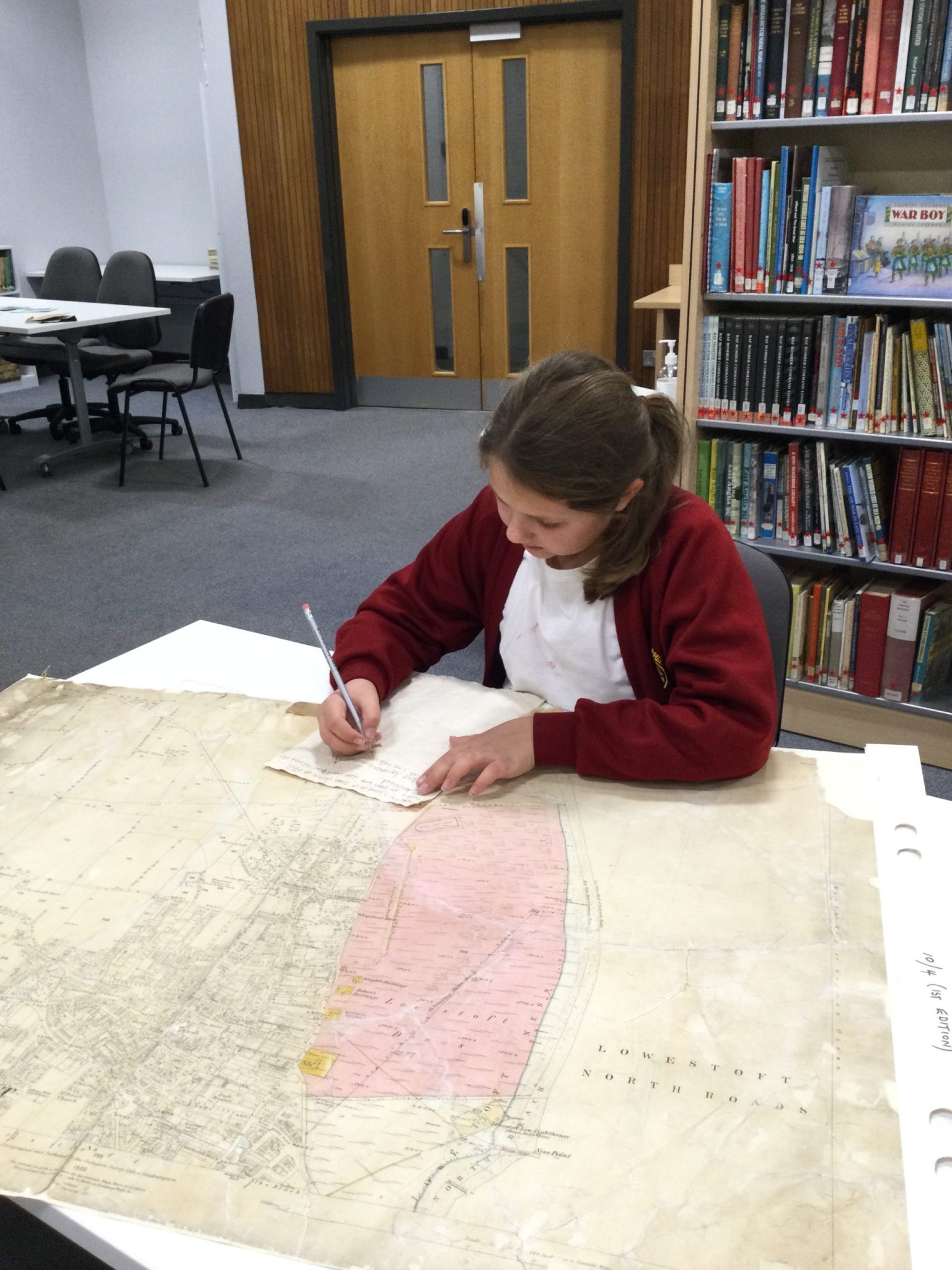 A child making notes about an old map of Lowestoft