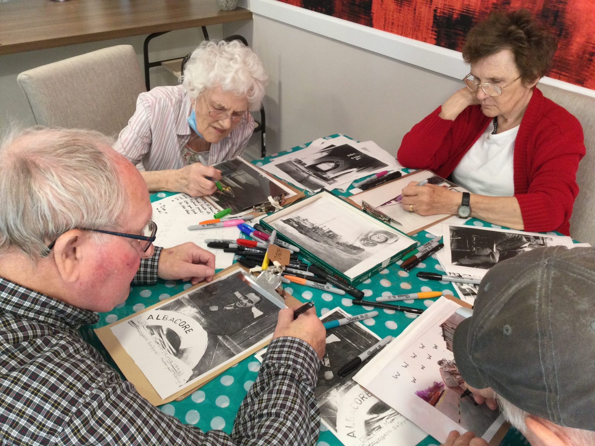 A group of four adults studying photographs and creating illustrations