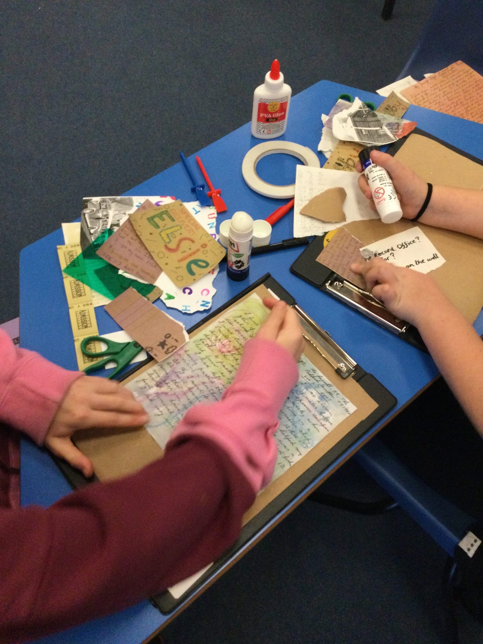 Children sticking down various cards and letters to create their collages