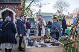 A group of Suffolk Artlink participants at our open garden in Kirkley. There are three people, assembling a willow structure for the Kirkley Pantry community garden.