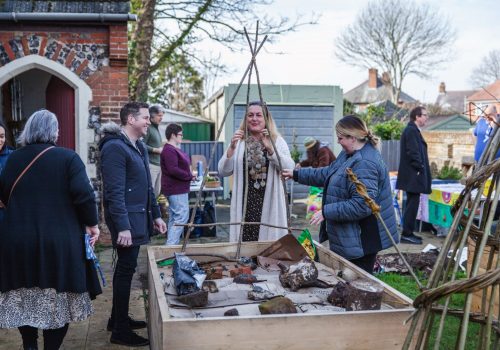 A group of Suffolk Artlink participants at our open garden in Kirkley. There are three people, assembling a willow structure for the Kirkley Pantry community garden.