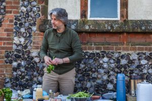 Our open garden celebration, led by Jon Tyler, commemorated the development of our Kirkley Pantry community garden. Jon Tyler stands in front of the group preparing food for the group members.