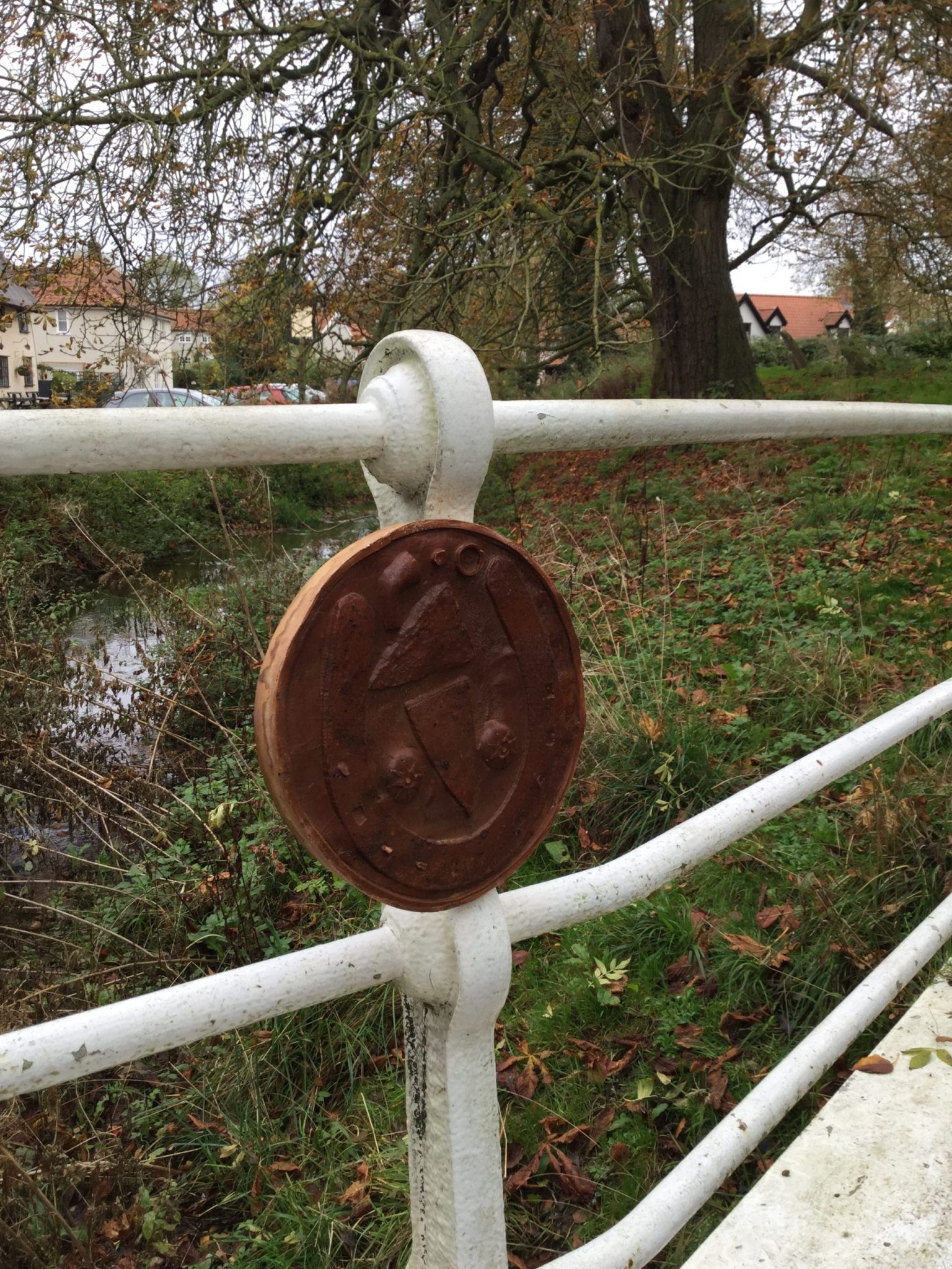 A brown circular plaque with a large horseshoe and two flat irons