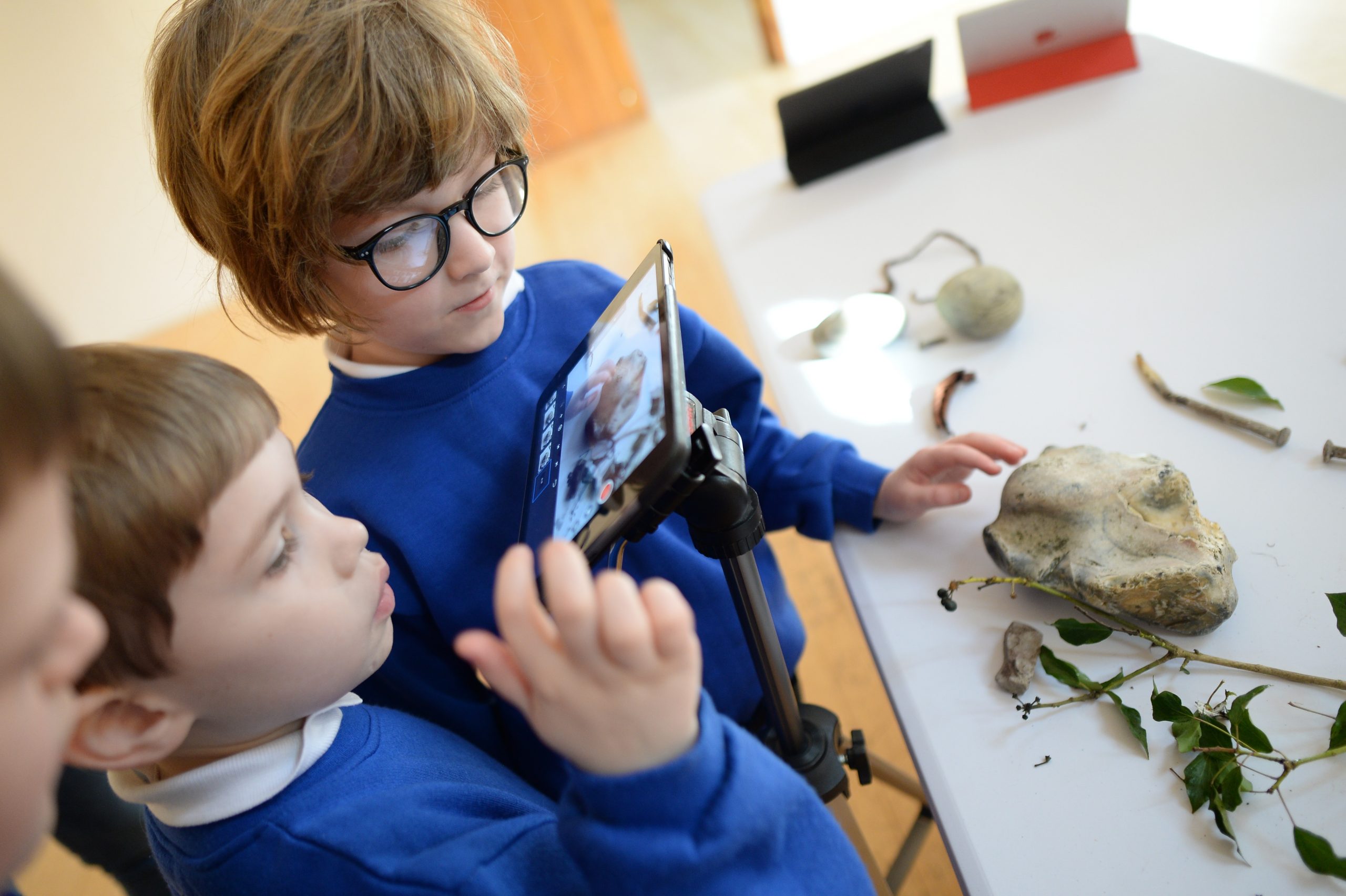 Two young school pupils viewing a nature table through the lens of an animation camera