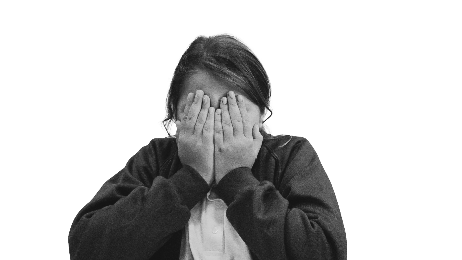 A monotone photograph of a child, covering her face with her hands