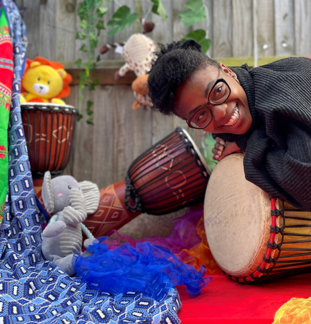 Sara Moreira with a blue juggling scarf with drums and cuddly toys.