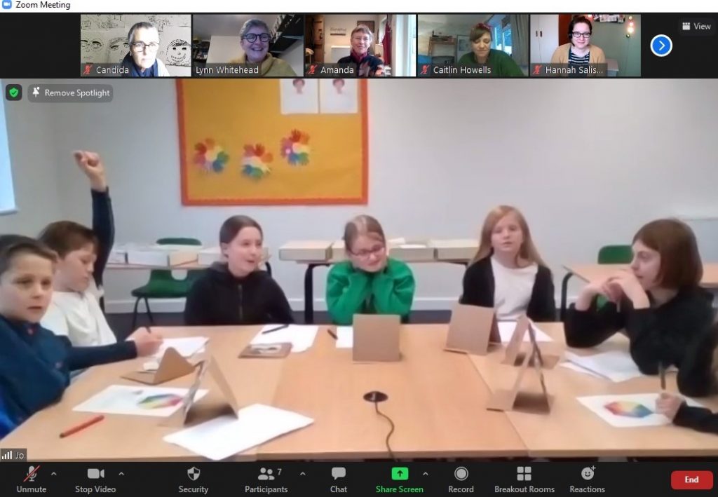 A group of school children seated around a table, taking part in a Zoom session