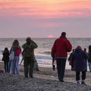 Crowd silloueted against sunset on a beach
