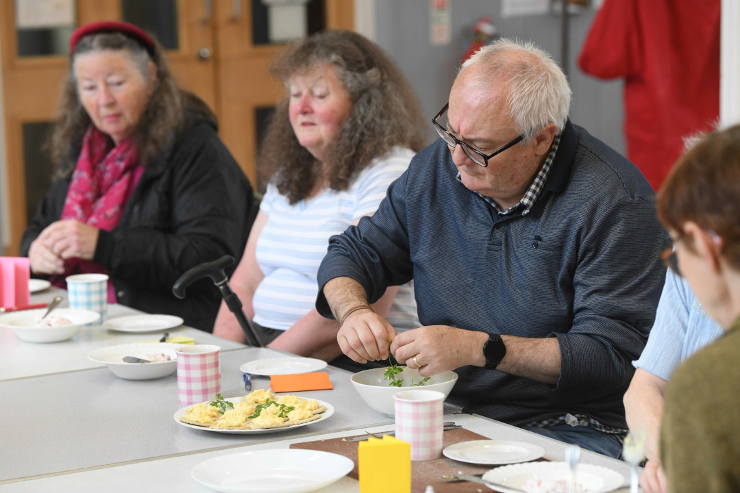 Four people sitting around a table creating a meal