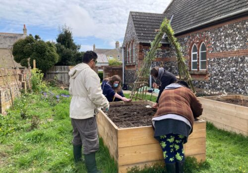 Participants around a raised bed in the Kirkley Pantry garden