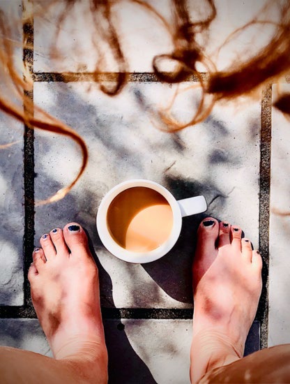 Looking down at mug of coffee between barefeet