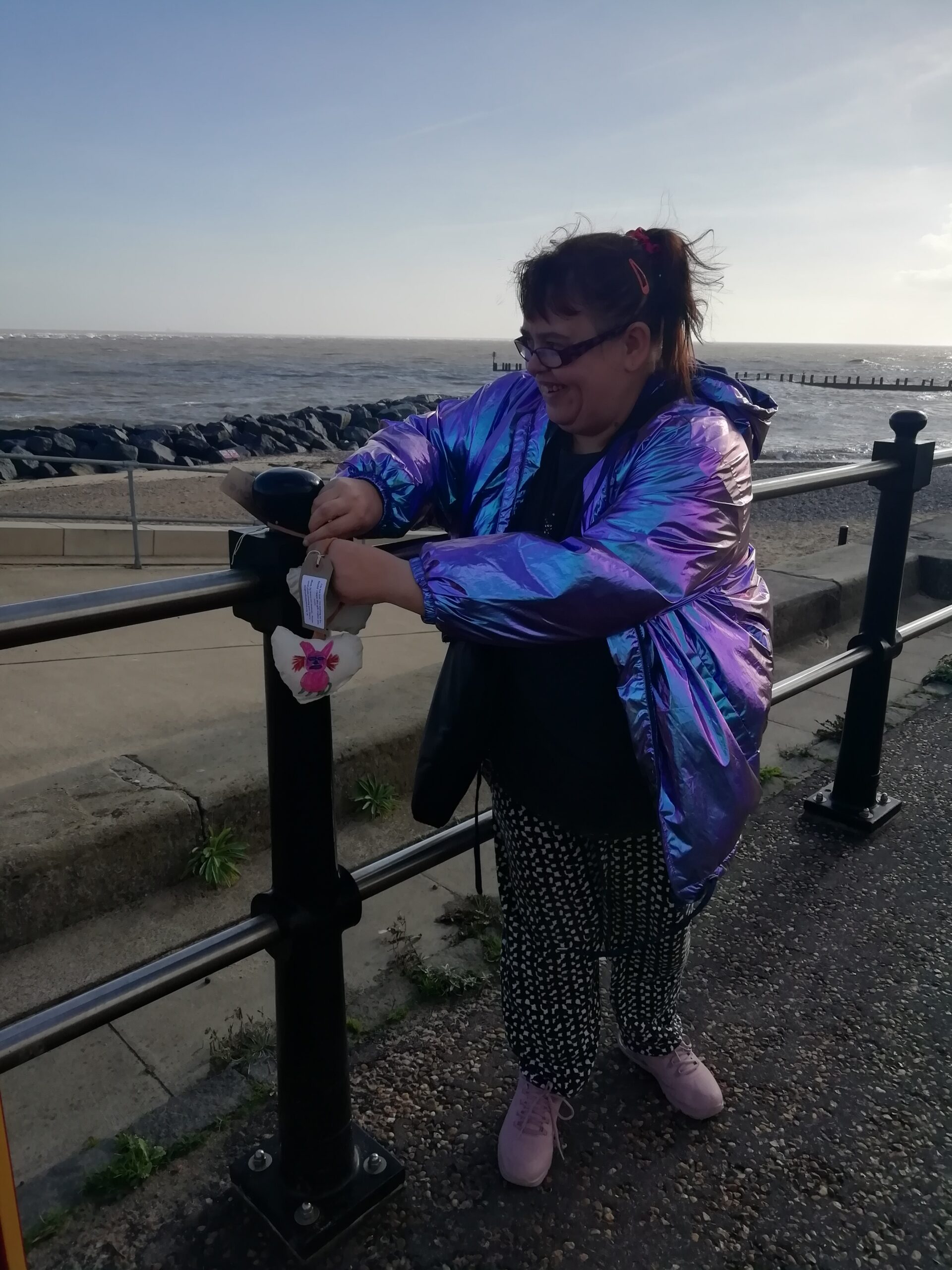 Brave Art student attaching heart with pink cat to seaside railings