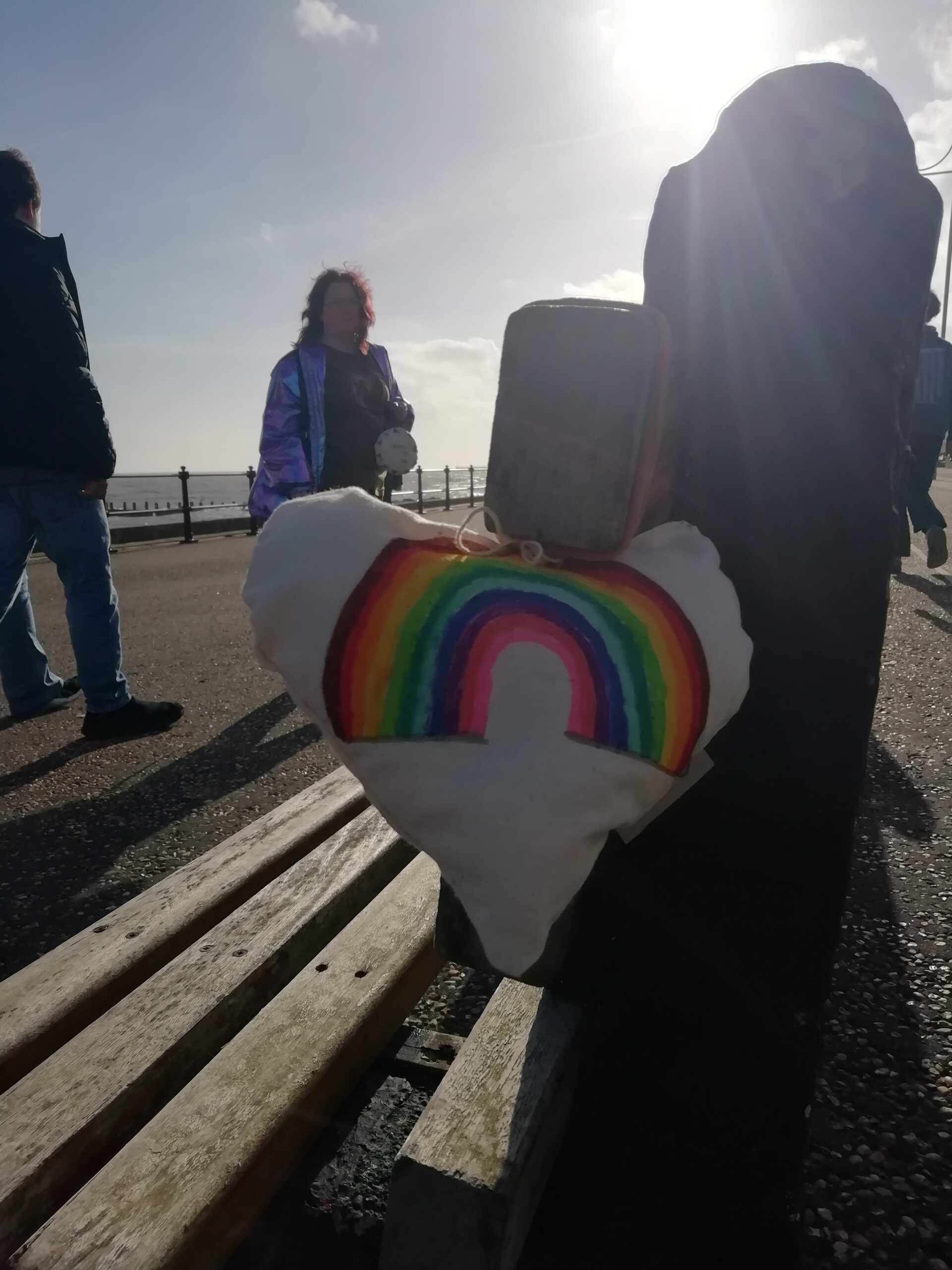 Heart with rainbow decoration hanging on the end of a seaside bench