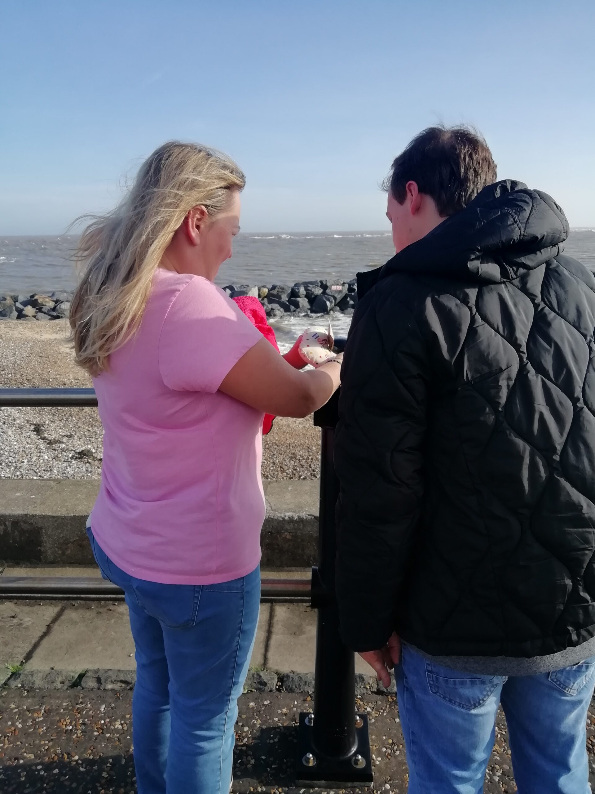 Brave Art participant and member of staff attaching Be Hopeful heart to promenade railings