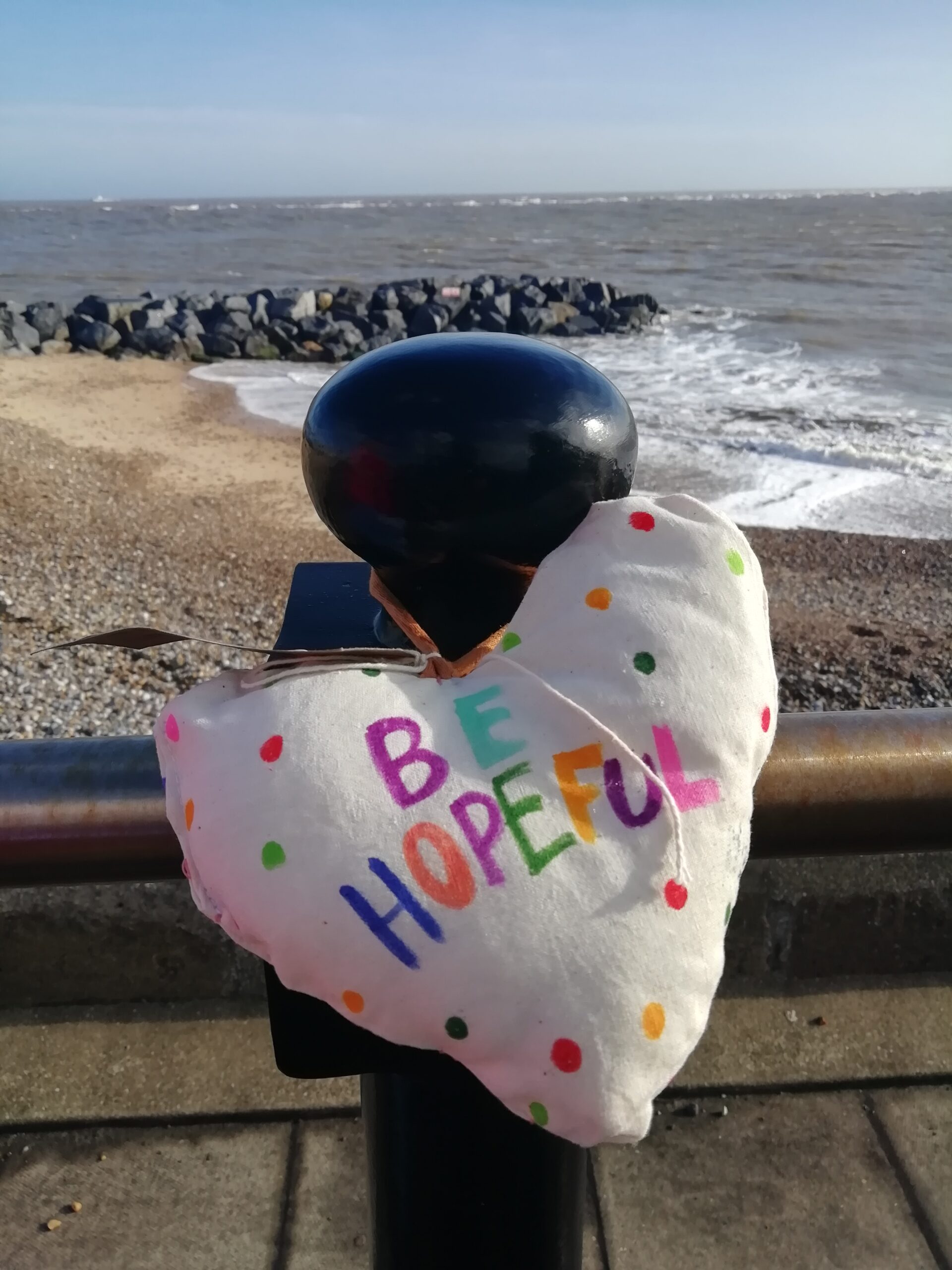 Close up of heart decorated with multicoloured dots and lettering saying 'Be hopeful'