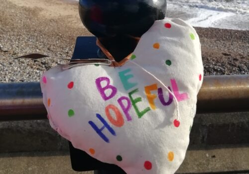 Close up of heart decorated with multicoloured dots and lettering saying 'Be hopeful'