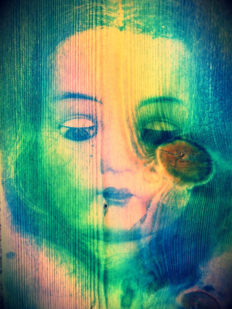 A coloured photograph of a doll's head printed on wood
