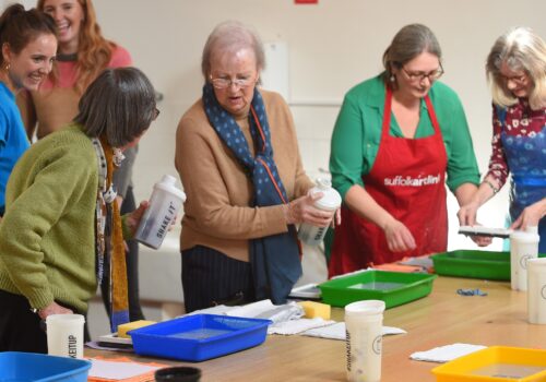 Participants taking part in a photography workshop standing around a table with developing trays.