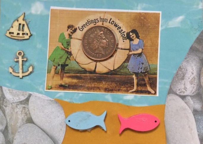 A vintage Greetings from Lowestoft postcard features in the centre; a 2-pence piece stuck in the centre of a lifebuoy. The image is laid over blue, sea-like paper and bordered by a small wooden boat and anchor to the left and a blue and pink fish below