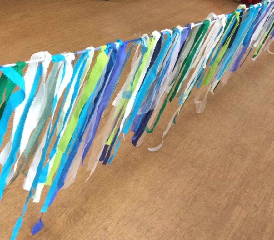 Strips of blue and green fabric tied onto yarn to make bunting