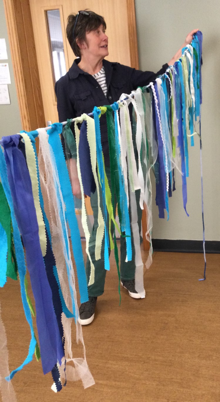 A long string of bunting made with strips of fabric in different shades of blue and green