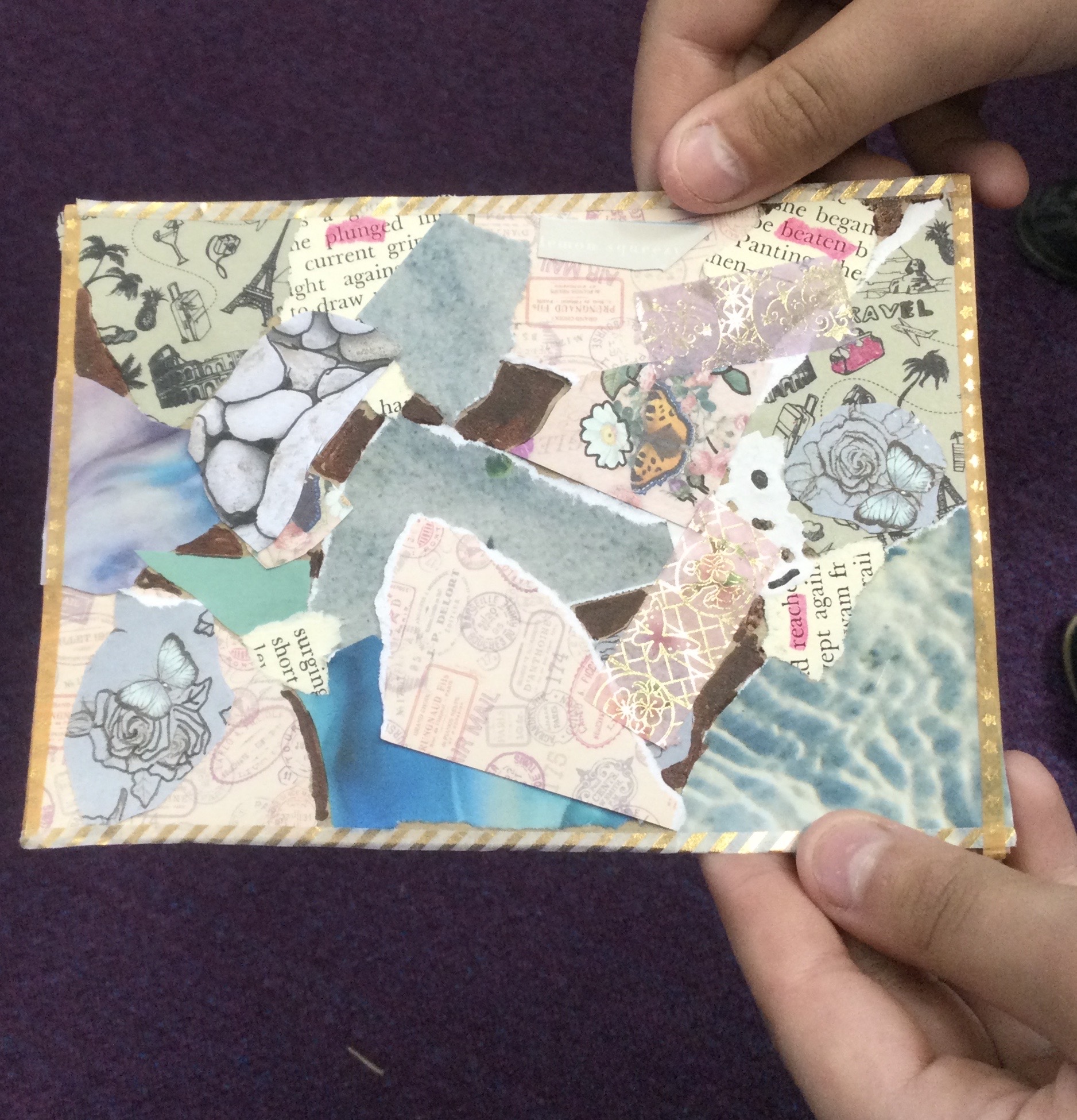 A pair of hands holding a postcard, collaged with a variety of papers in pinks and blues, some with images of palm trees and bordered with a thin gold tape