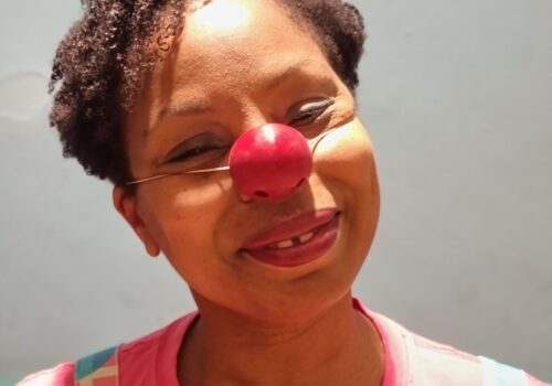 Clown Doctor Dr Kit Kat AKA actor, Katrina Beckford, wearing a red nose and smiling.