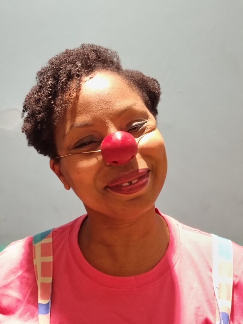 Clown Doctor Dr Kit Kat AKA actor, Katrina Beckford, wearing a red nose and smiling.