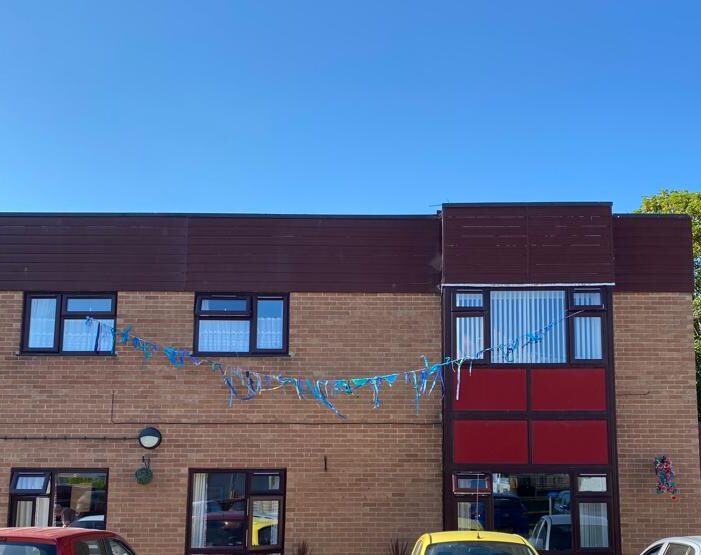 Blue bunting suspended between two upper windows against a brilliant blue sky