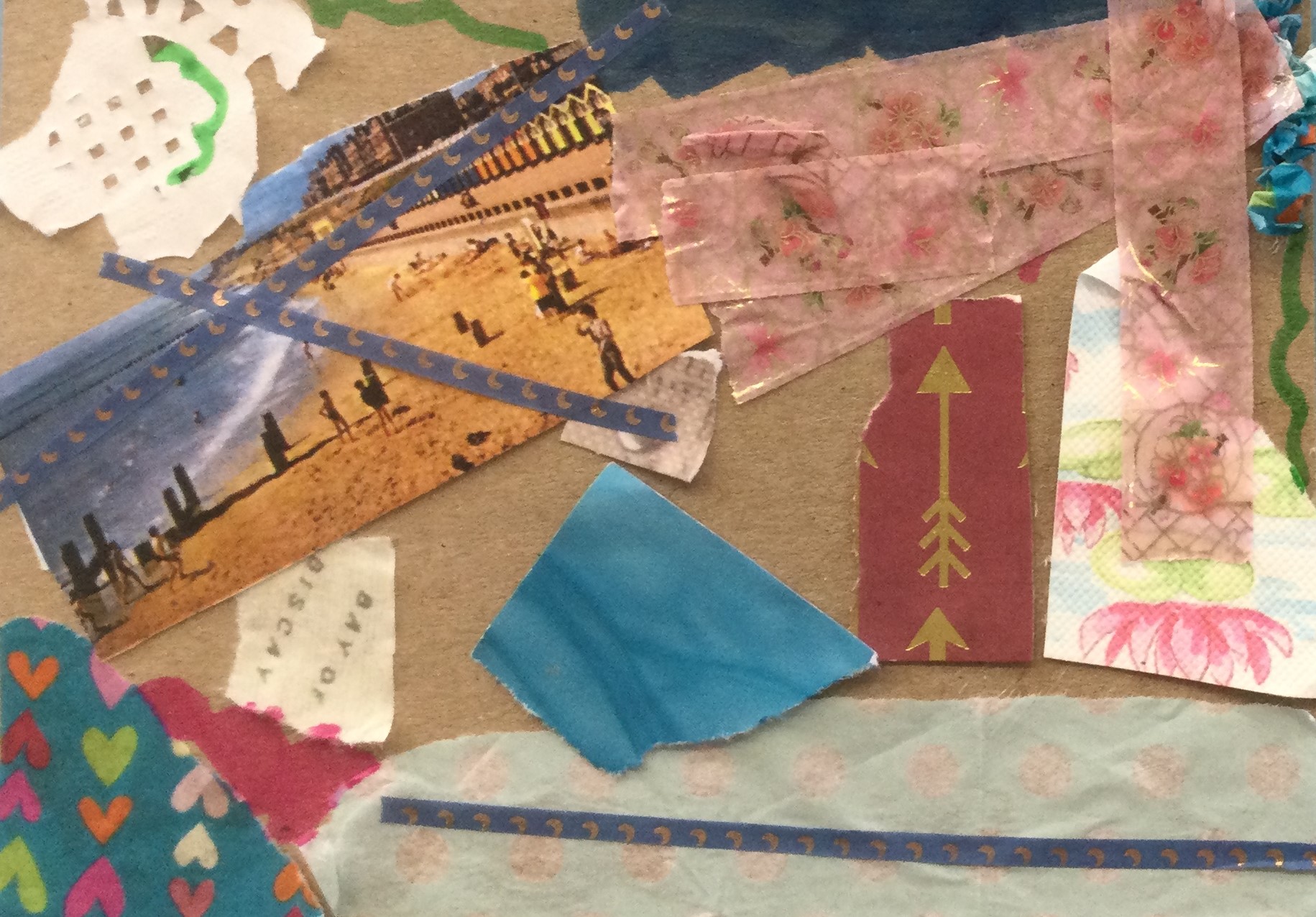 A collaged postcard decorated with many little bits of paper, including a snippet of a vintage postcard showing people on a sunny beach, scraps of blue and pink papers, a piece with text reading Bay of Biscay and strips of thin blue and gold tape. There is also a piece of reddish brown paper with a gold arrow pointing to the top of the card