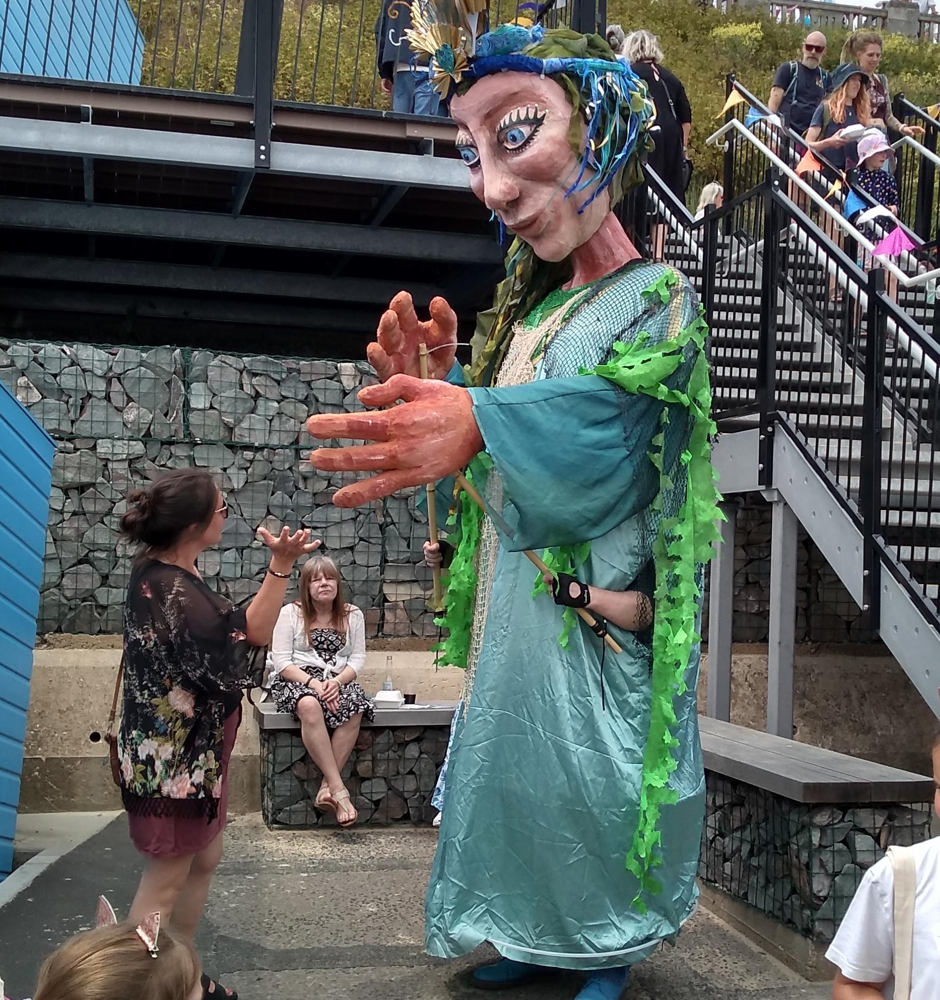 The masssive puppet Sol, depicting the Spirit of the Sea, engaging with a member of the public