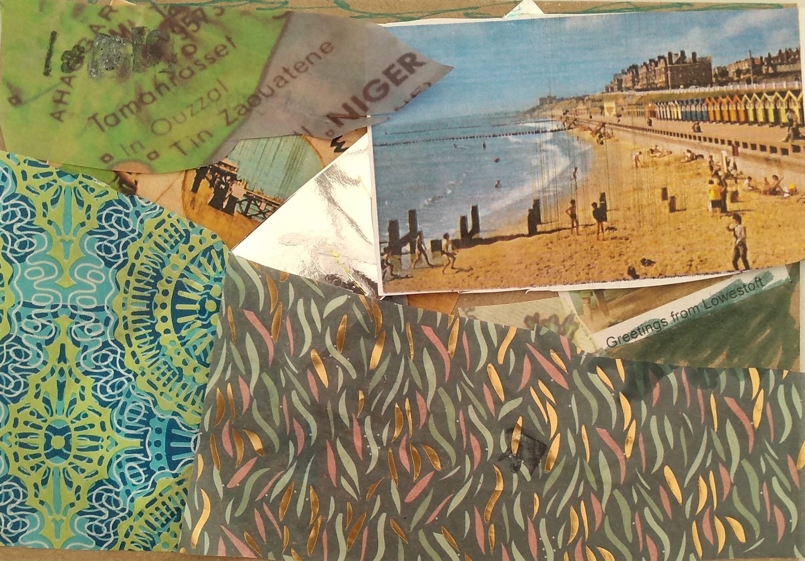 A collaged postcard with a vintage postcard image showing people playing on the beach in front of a line of beach huts. There is also grey, gold and bronze flecked patterned paper below and blue,gold to the left, overlaid with snippets of a map