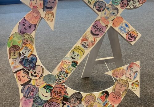 Photograph of an artwork featuring a hardboard anchor covered in the self-portraits of Brave Art students.