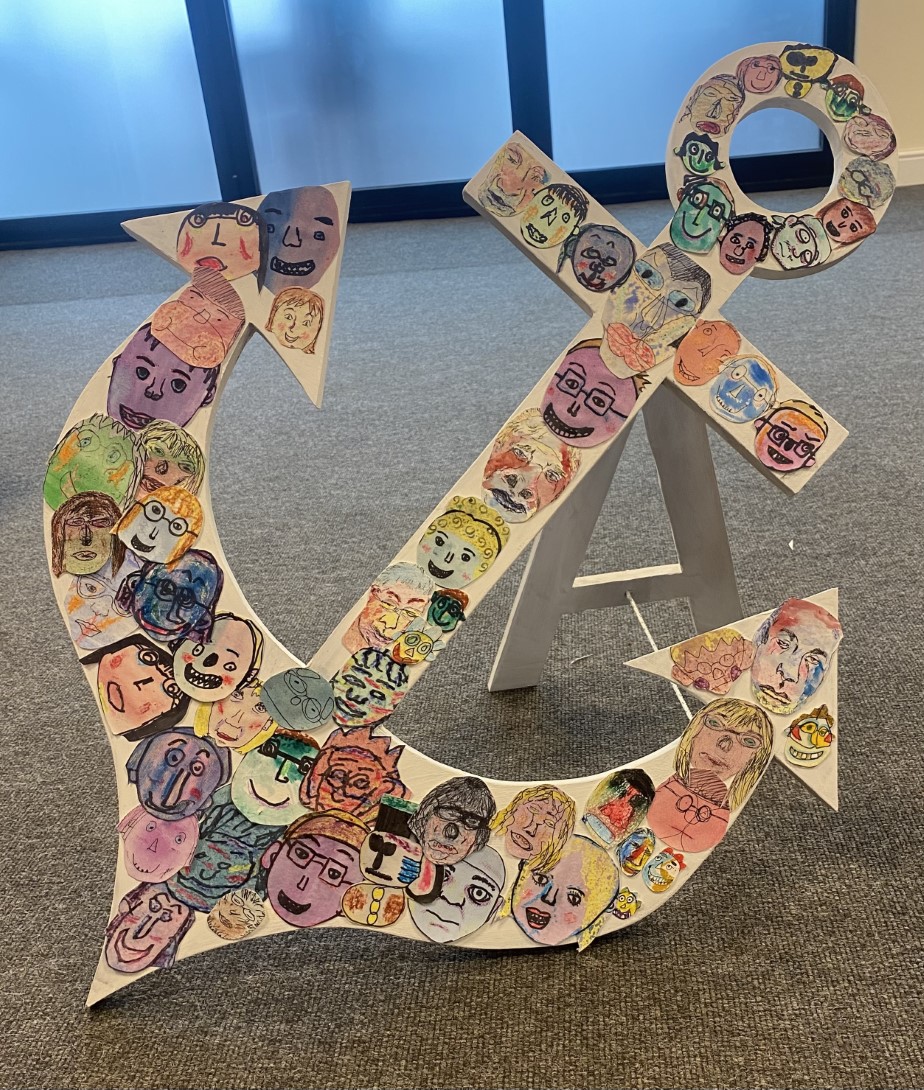 Photograph of an artwork featuring a hardboard anchor covered in the self-portraits of Brave Art students.